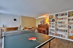 A room with a ping pong table, a piano, a bookshelf, and a sofa. - Charming multi-level 3 Bedroom home 15 minutes from Killington Mountain (Killington)
