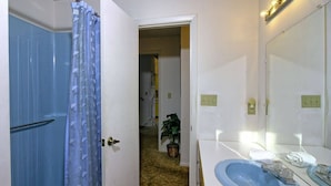 Une salle de bain avec un lavabo bleu, un miroir avec éclairage intégré et un rideau de douche.
