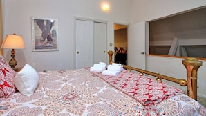 Une chambre d’hôtel avec un lit, une lampe de chevet, un miroir et un tableau encadré au mur.