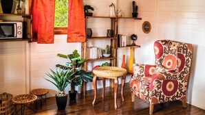 Une pièce chaleureuse avec un plafond en bois, un fauteuil rouge, une petite table et diverses plantes.