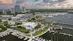 A marina with multiple docks and boats, surrounded by buildings and greenery.