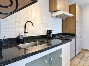 Cozinha moderna com bancada de granito, pia de aço inoxidável e cafeteira.
