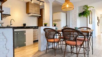 Una cocina moderna con una isla central, sillas de comedor y una lámpara colgante.
