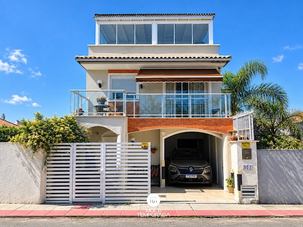 A two-story house with a garage, a balcony, and a clear sky. - Ap. Aconchego do Campeche (Florianópolis)