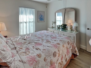 A bedroom with a bed, dresser, and window with blinds. - Estero Cove 341 (Fort Myers Beach)
