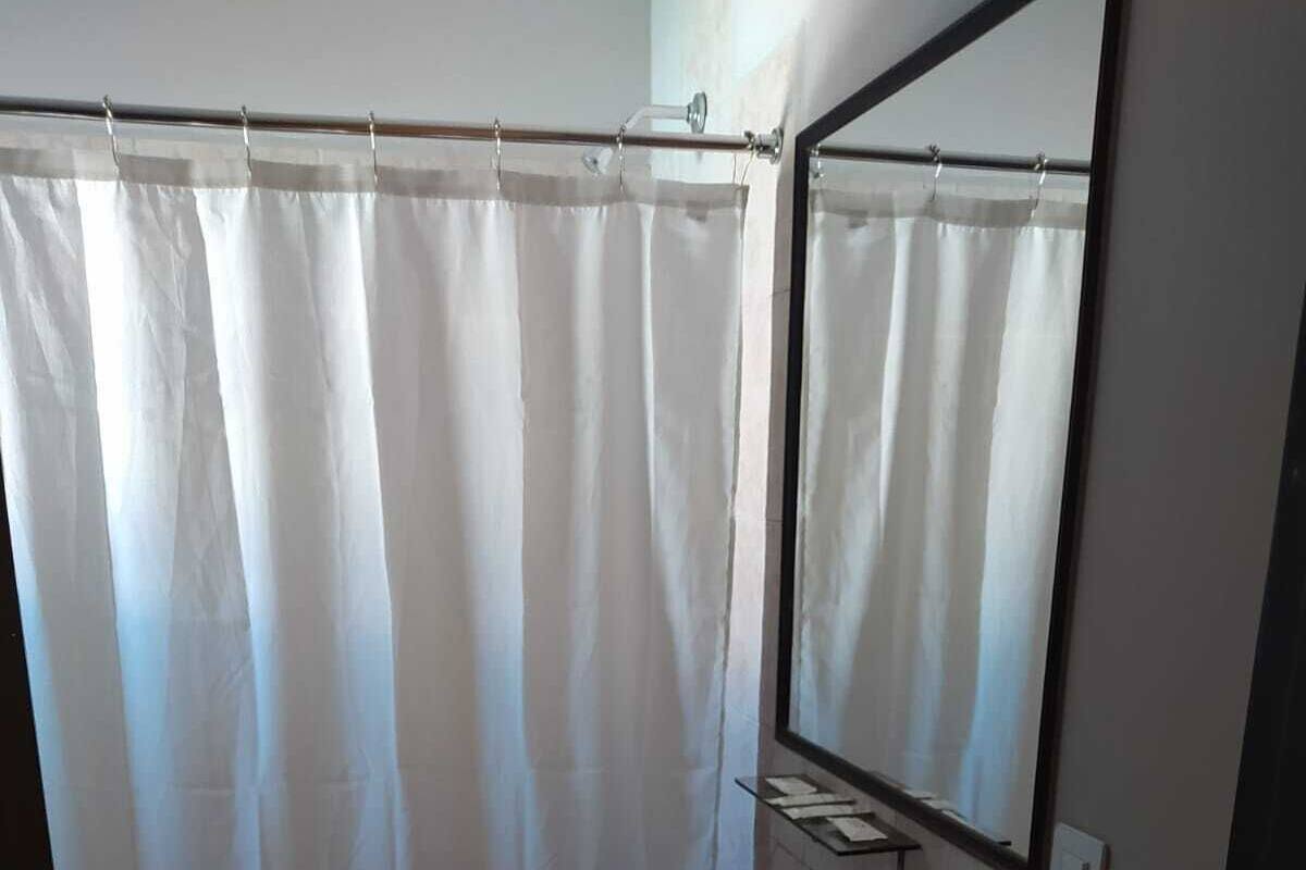 Ein Badezimmer mit Duschvorhang, Waschbecken, Spiegel und Handtuchhalter.