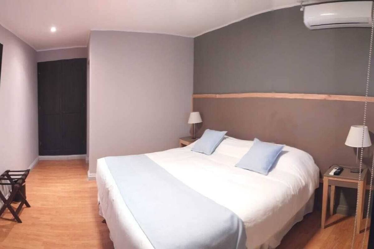 Ein Hotelzimmer mit Bett, Nachttischen, Fernseher und Kleiderschrank.