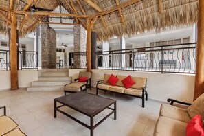 A spacious indoor area with a high ceiling, a thatched roof, and a view of a building outside.