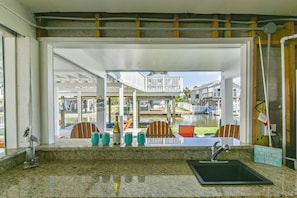 Enjoy a view of the pool area from this kitchen, featuring a large window, granite countertop, sink, and wine cooler.