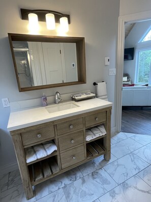 A bathroom with a wooden vanity, a large mirror, and a sink. - Relax and Revitalize at Sprucewood Cottage (Port Blandford)