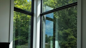Une chambre d’angle dotée de grandes fenêtres donnant sur une zone boisée.