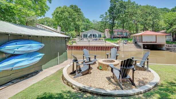 A backyard with a fire pit, outdoor seating, and a boat storage area. - Spacious Deck: Waterfront Home in Gun Barrel City! (Gun Barrel City)