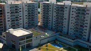 Een modern appartementencomplex met meerdere hoge gebouwen, een centrale binnenplaats en een zwembad.