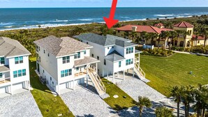 A coastal residential area with modern houses, a clear view of the ocean, and a prominent red arrow pointing to a specific house. - Beachside Beauty (Palm Coast)