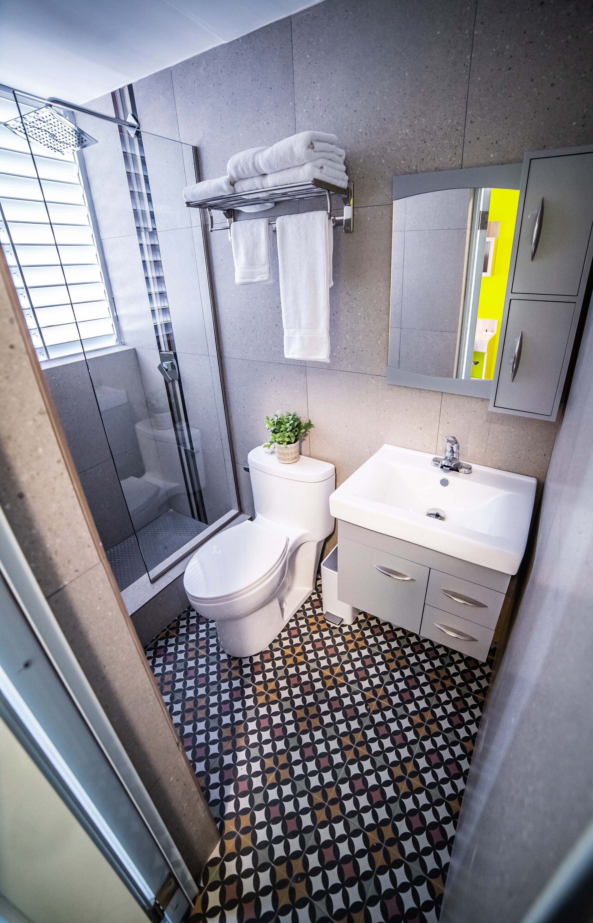 A modern bathroom with a shower, toilet, sink, and a patterned floor.