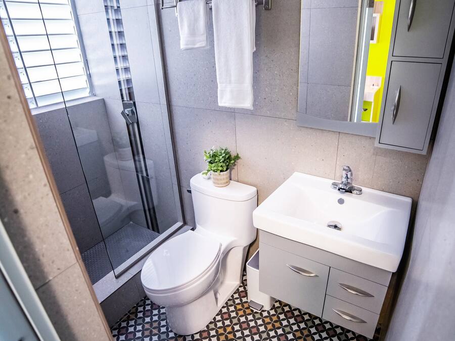 A modern bathroom with a shower, toilet, sink, and a patterned floor.