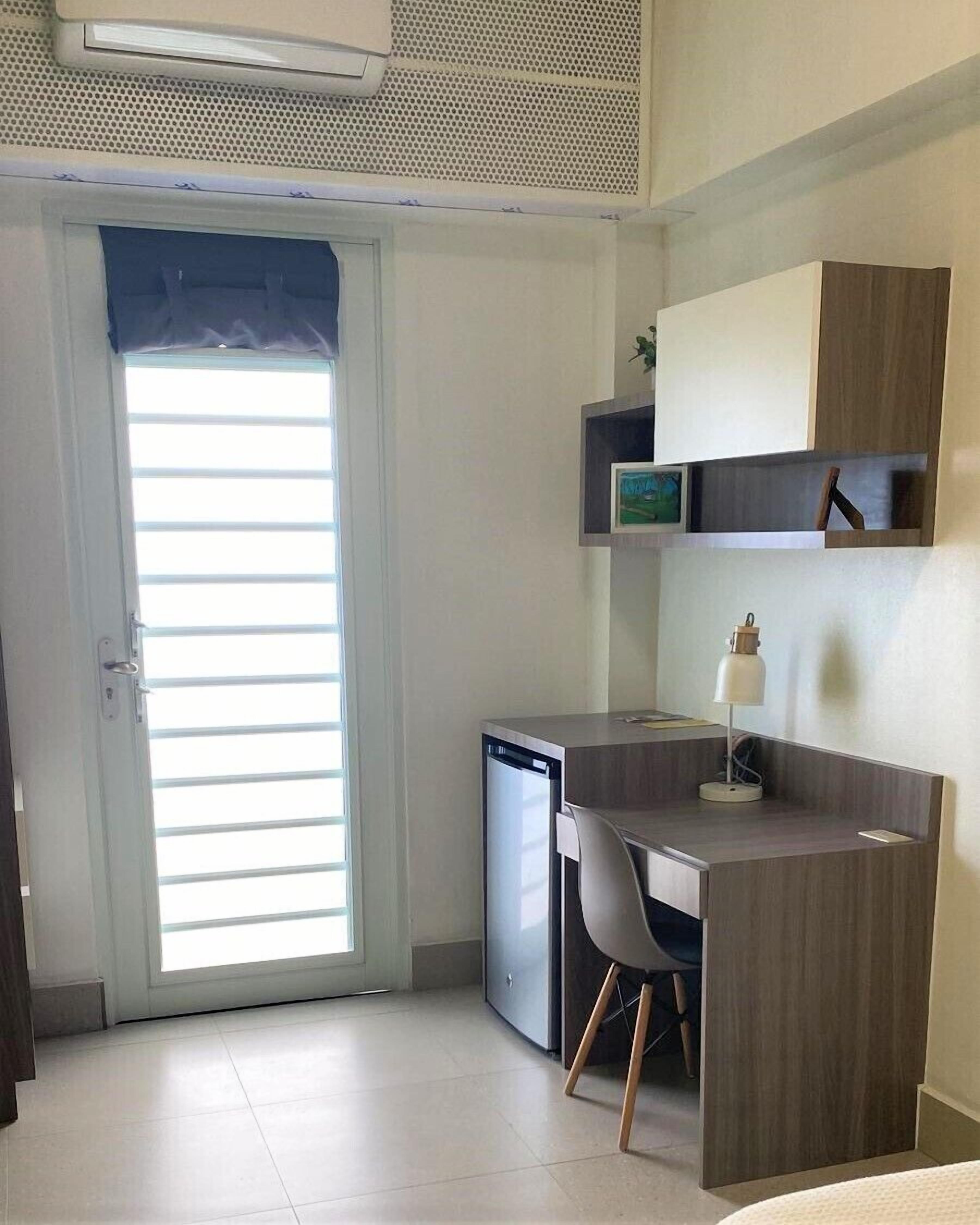 A compact room with a desk, chair, and a small cabinet.