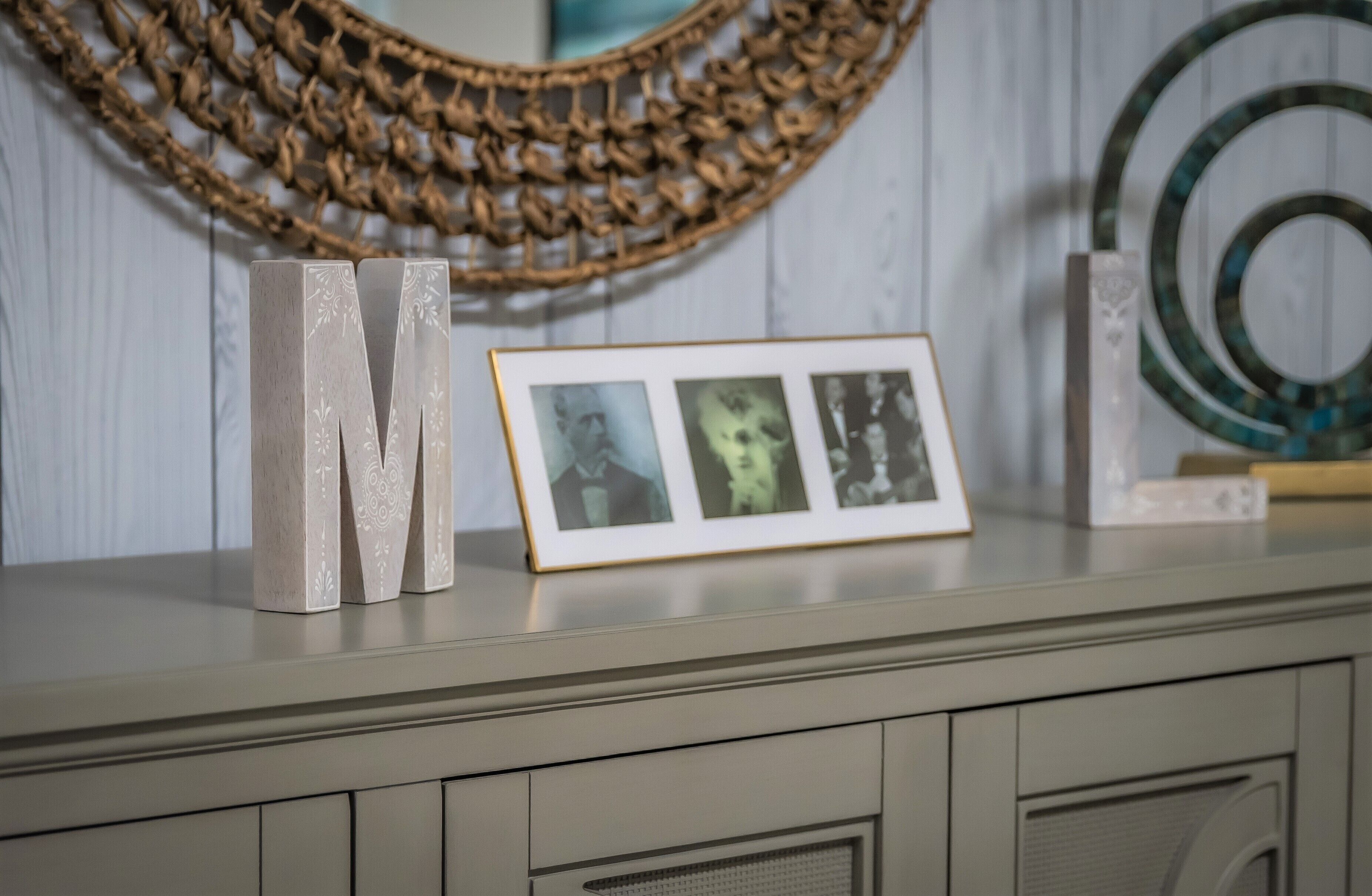 A framed photograph on a shelf, a decorative wall hanging, and a circular object.