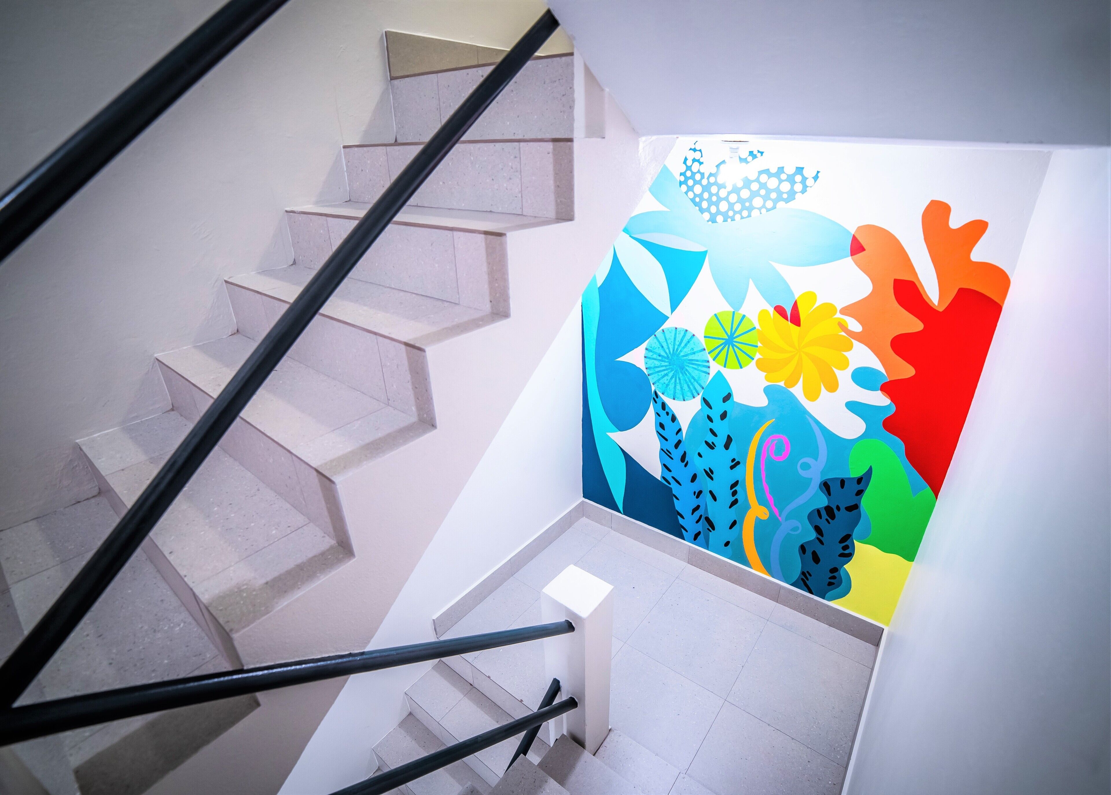 A staircase with a handrail and a colorful wall mural.
