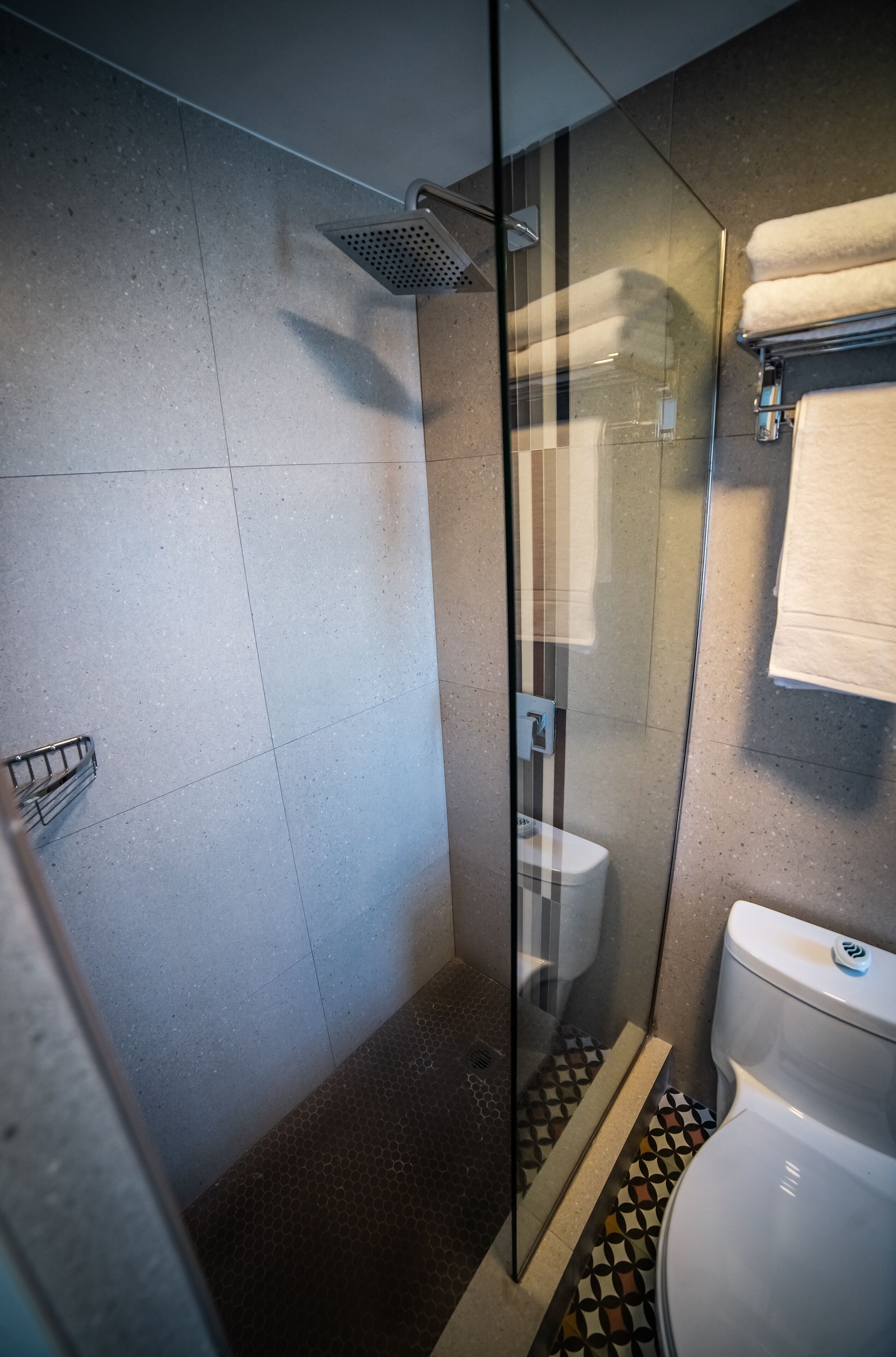 Un bagno moderno con doccia vetro, un water e pavimento decorato.