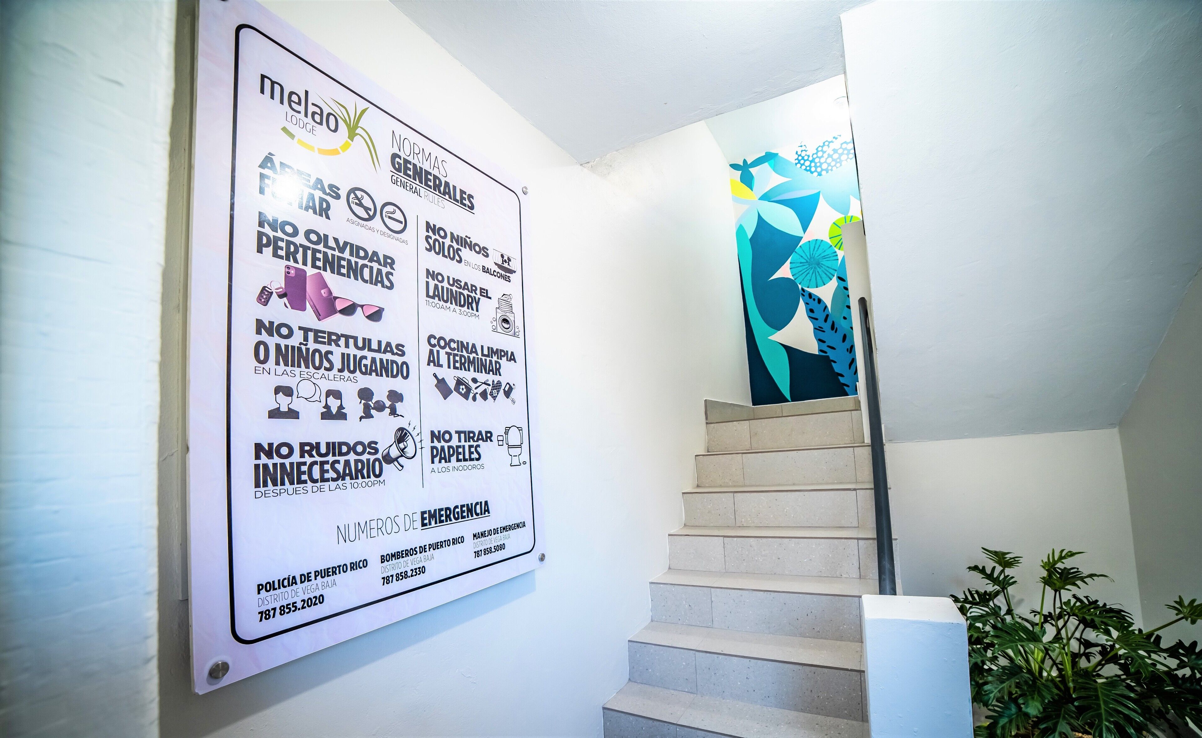 Eine Treppe mit einem Schild, das Hotelrichtlinien und Notrufnummern auflistet.