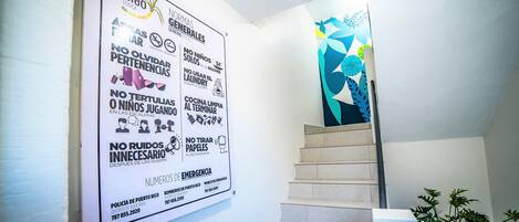 Una escalera con un letrero que enumera las normas del hotel y números de emergencia.