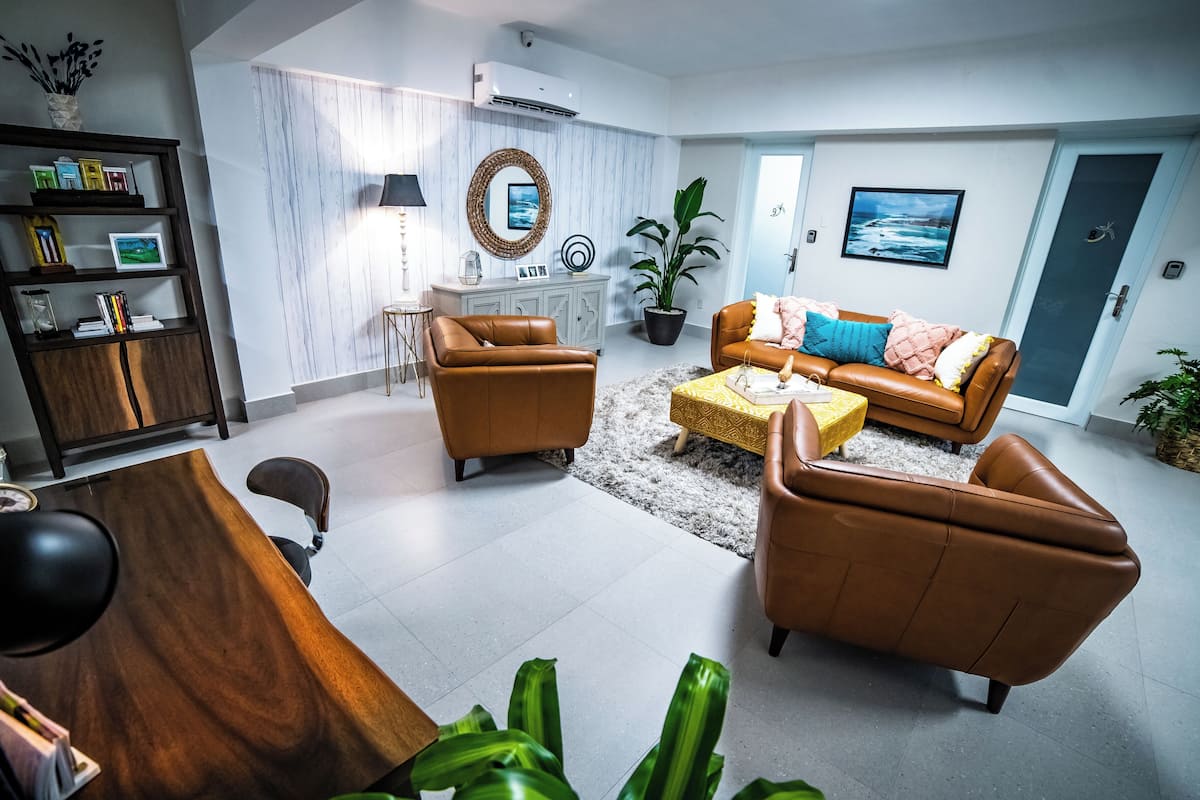 Ein modernes Wohnzimmer mit einem braunen Ledersofa, einem Holzesstisch und einer Wand mit weißem Marmor.