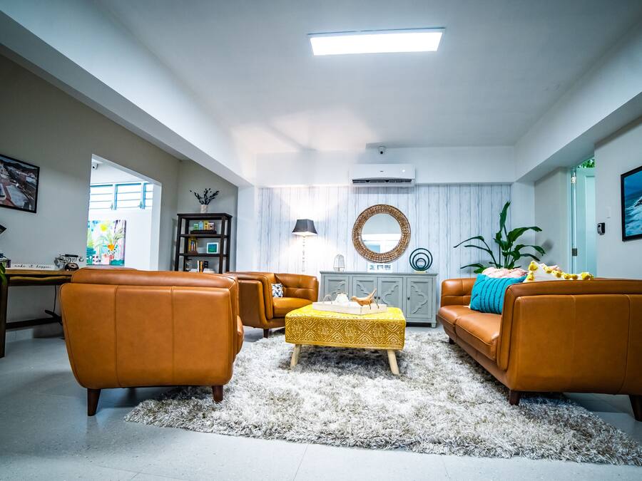 Ein geräumiges Wohnzimmer mit hoher Decke, einem großen Fenster und Blick ins Freie.