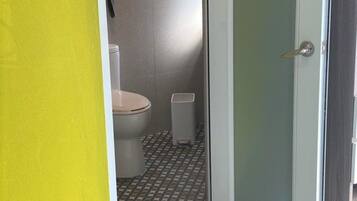 Une salle de bain comprenant des toilettes, un lavabo et un espace douche.