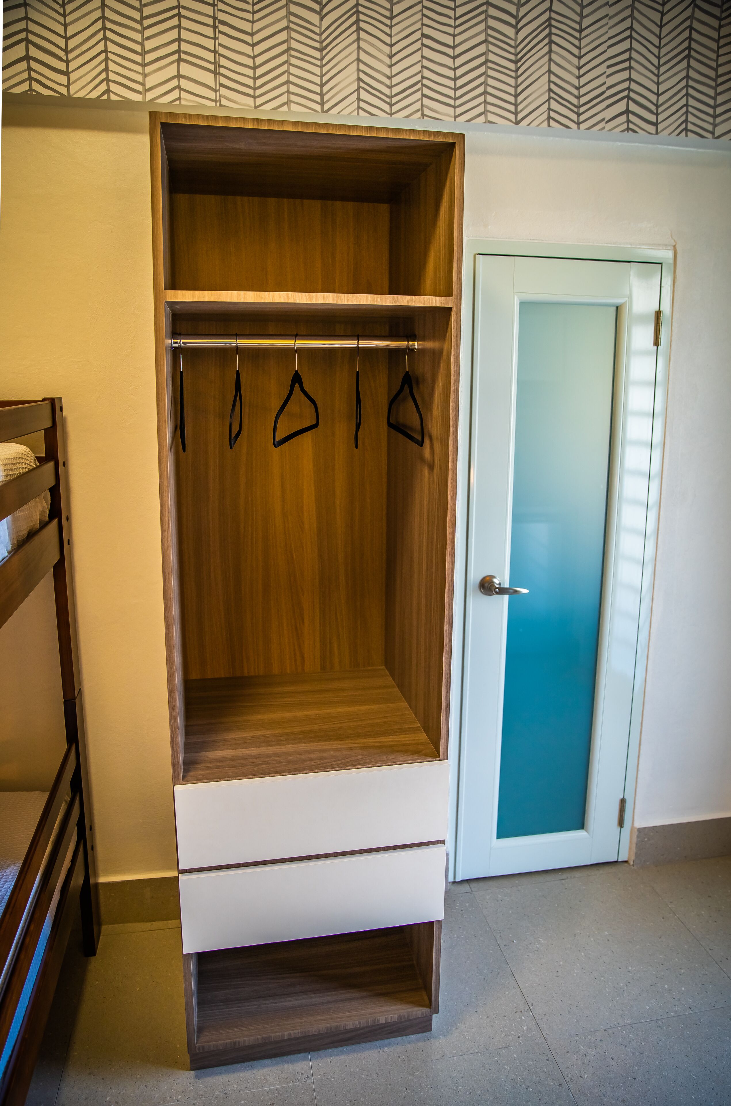 A walk-in closet with wooden shelving, a hanging rod, and a sliding door.