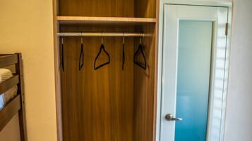 A walk-in closet with wooden shelving, a hanging rod, and a sliding door.