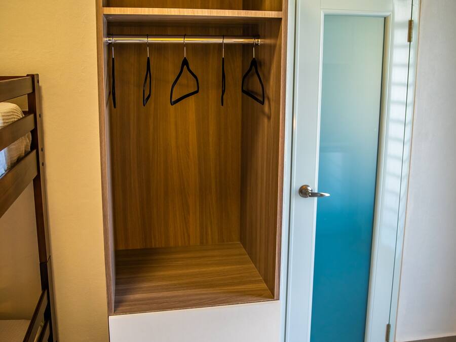 A walk-in closet with wooden shelving, a hanging rod, and a sliding door.