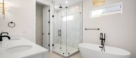 Une salle de bain moderne dotée d’une douche à parois de verre, d’une baignoire sur pieds et d’un meuble-lavabo.