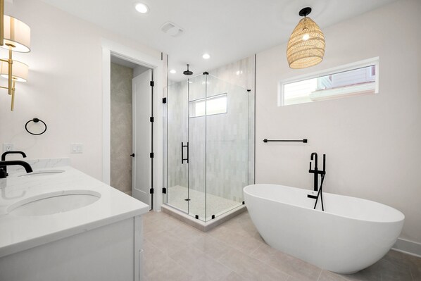 A modern bathroom with a glass-enclosed shower, a freestanding bathtub, and a vanity with a sink.