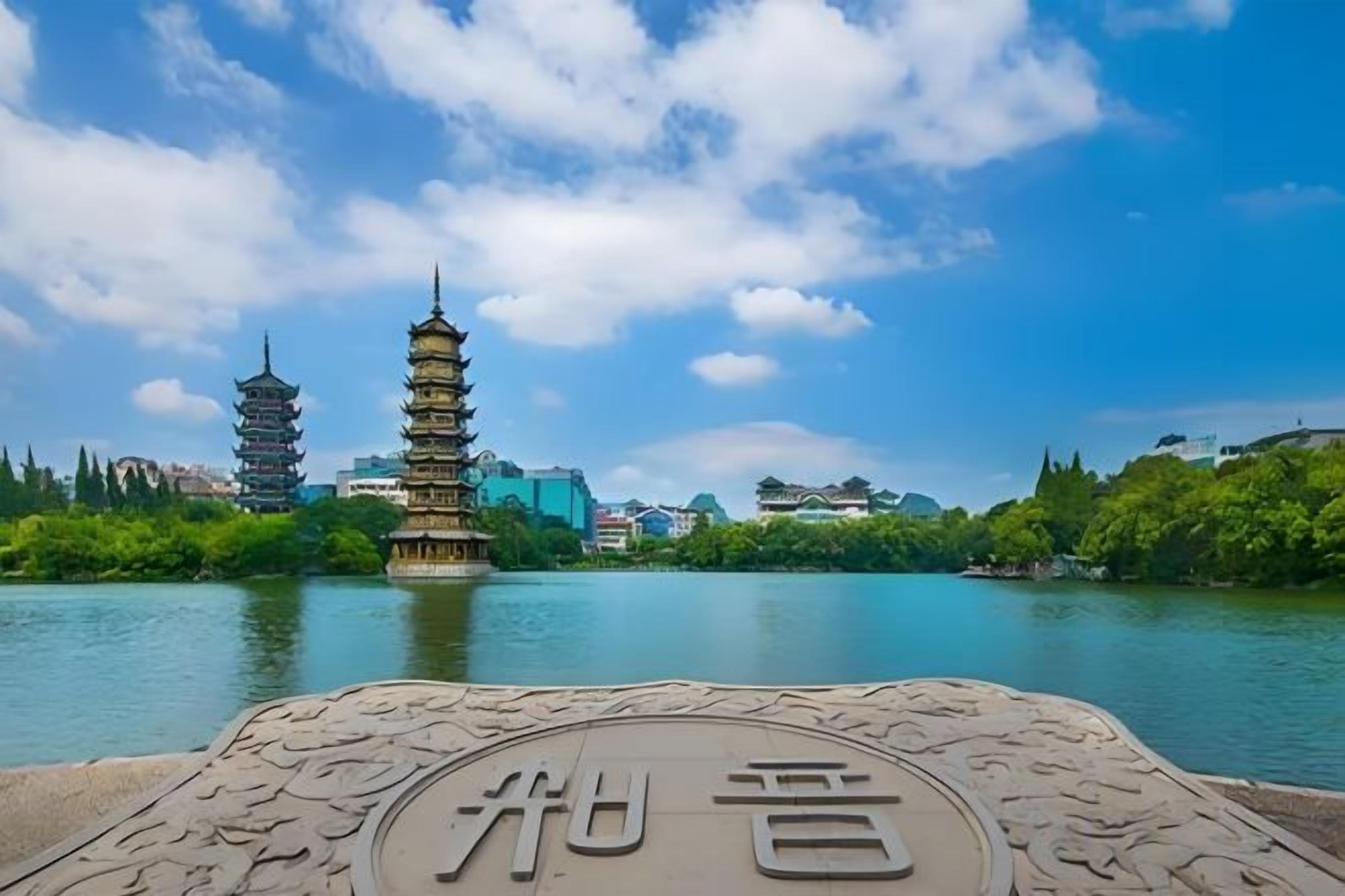 A pagoda-style tower by a body of water with a stone plaque in the foreground.