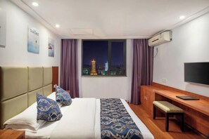 A hotel room with a bed, a desk, a bench, and a TV. - Lixin Hotel (Guilin Sun Moon Twin Pagodas & Elephant Trunk Hill Scenic Area Branch) (Guilin)