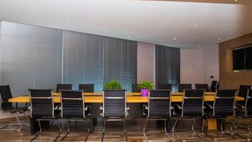 Une salle de conférence avec une longue table, des chaises et une plante.
