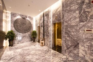 A marble-floored hallway with a circular wall design, a reception area, and a gold elevator. - Horgos Hotel (Khorgas)