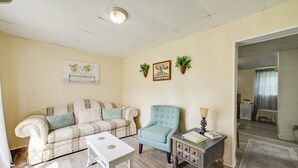 A living room with a sofa, a chair, a small table, and a side table with a lamp. There are two wall-mounted planters and a framed picture on the wall. - Serene McEwen Cottage ~ 2 Mi to Golf Course! (McEwen)