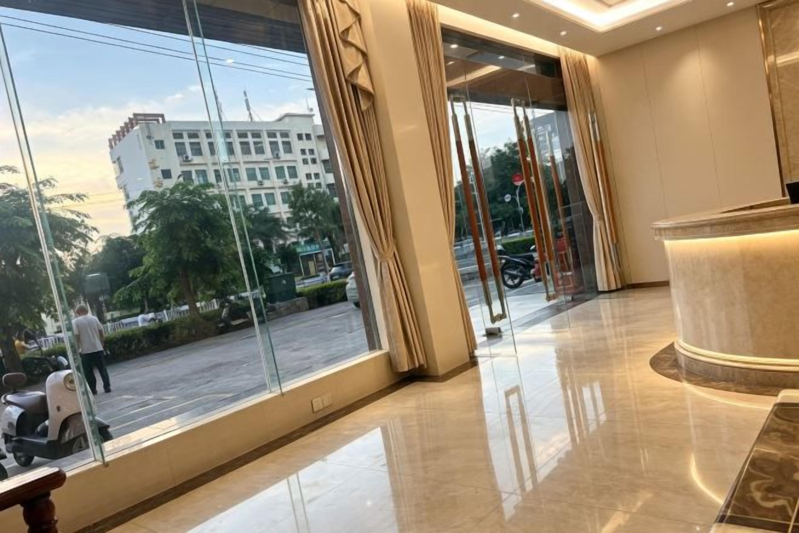A hotel lobby with large windows, a reception desk, and a polished floor.