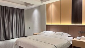 A modern hotel room with a large bed, a bedside table with a lamp, and a wardrobe with illuminated panels. - Dongfang Guanda Business Hotel (Dongfang)