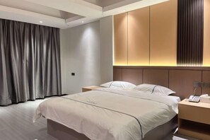 A modern hotel room with a large bed, a bedside table with a lamp, and a wardrobe with illuminated panels.