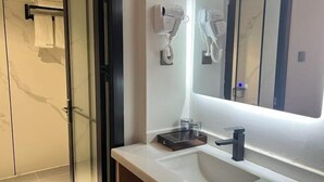A modern bathroom with a large mirror, a hairdryer, and a towel rack. - Dongfang Guanda Business Hotel (Dongfang)