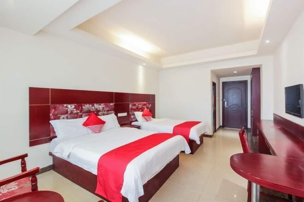 Een hotelkamer met twee bedden, een televisie en een bureau.