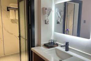 A modern bathroom with a large mirror, a hairdryer, and a towel rack.
