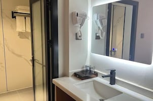 Un baño moderno con un espejo grande, un secador de pelo y un perchero para toallas.