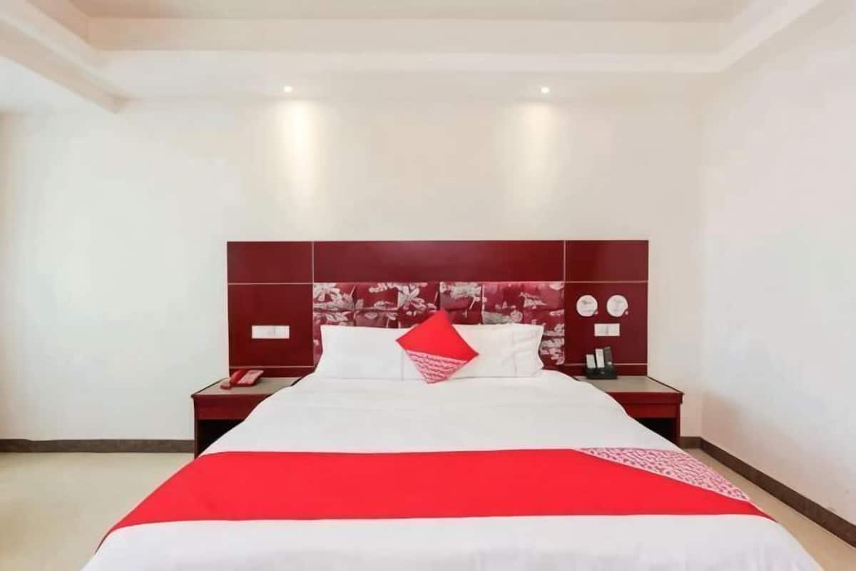 Een hotelkamer met een groot bed, twee nachtkastjes en een kleurenschema van rood en wit.