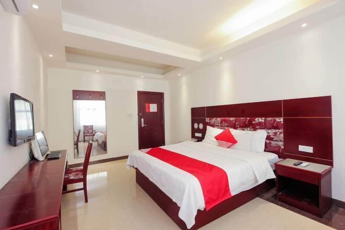 Hotelkamer met een groot bed, een bureau met een computer, een stoel en een nachtkastje met een telefoon.
