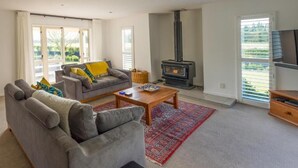 Una sala de estar con un sofá gris, una mesa de centro, una alfombra roja, una chimenea y un televisor sobre un mueble de madera.
