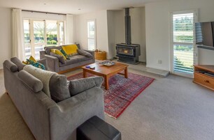 Una sala de estar con un sofá gris, una mesa de centro, una alfombra roja, una chimenea y un televisor sobre un mueble de madera.
